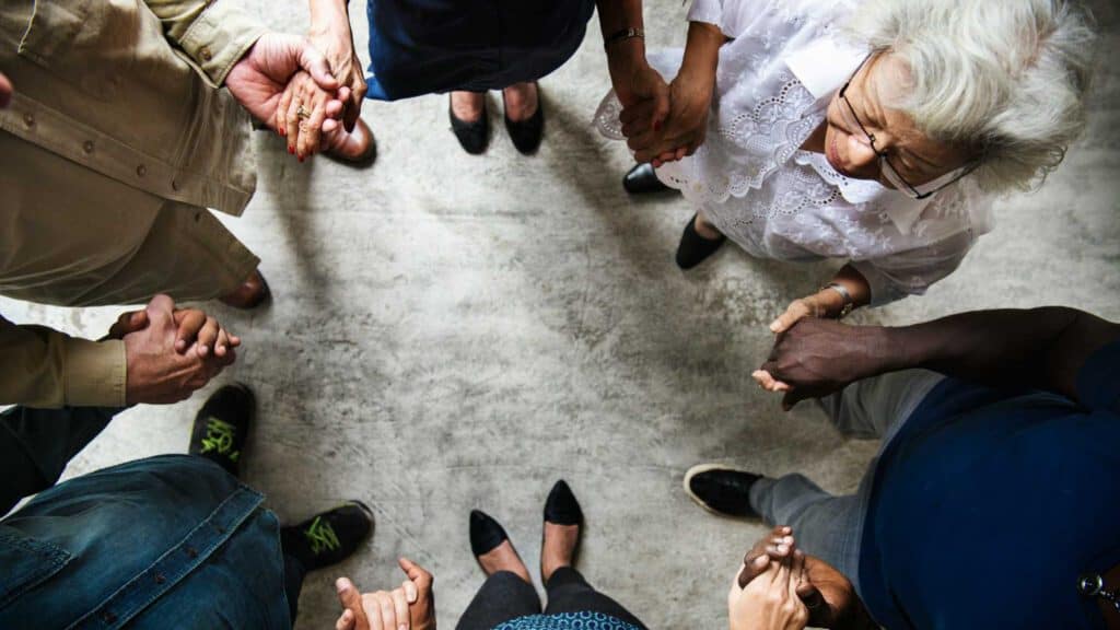 A diverse church group praying together conveys the message of the blog post titled "Let The Church Be The Church".