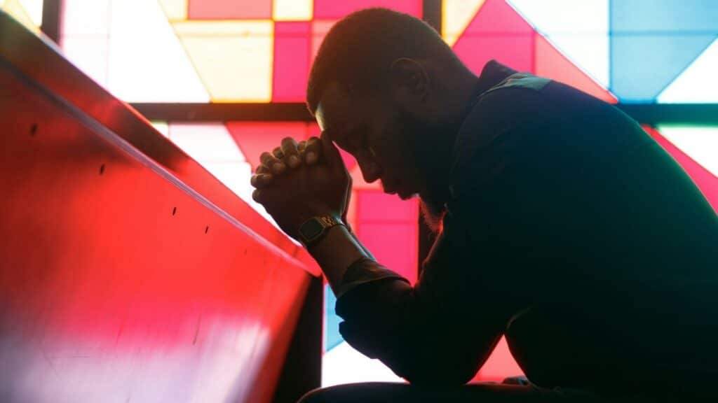 Man prays in a church, relying on the power of prayer from Phillippians 4:6-7.